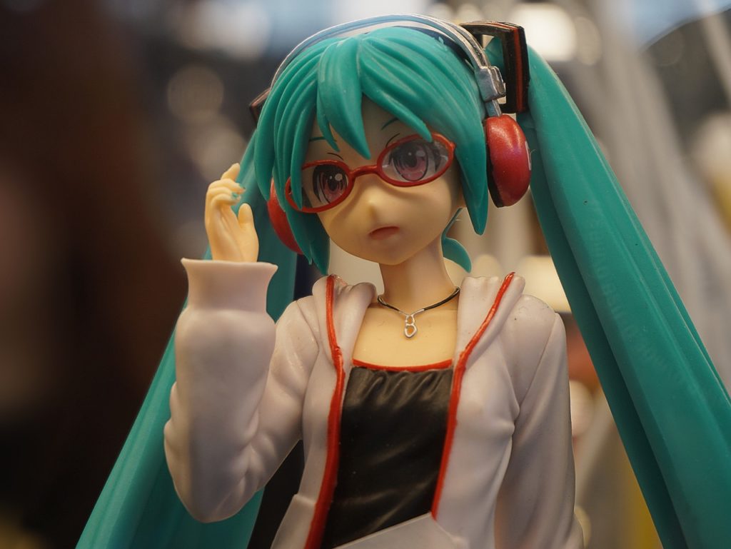 figurine anime aux cheveux turquoise avec lunettes rouges et casque audio