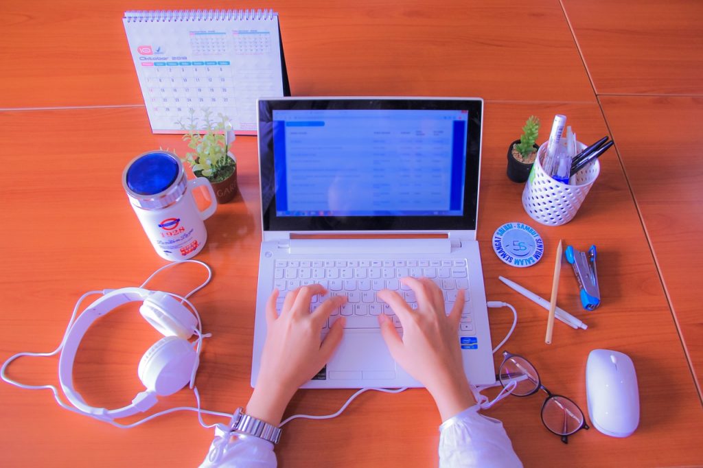 personne travaillant sur un ordinateur portable à son bureau avec accessoires de travail