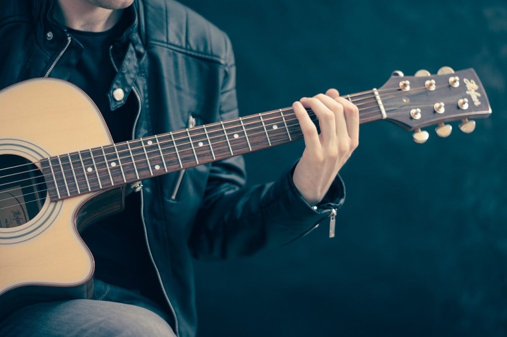 musicien jouant de la guitare acoustique sur fond bleu