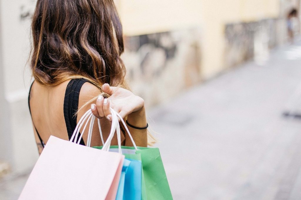 femme de dos avec des sacs de shopping colorés dans une rue