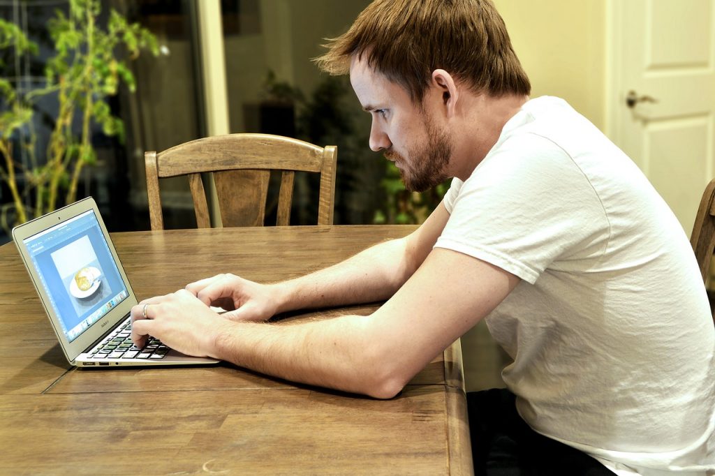 homme travaillant sur un ordinateur portable avec une interface de design Adobe XD affichée