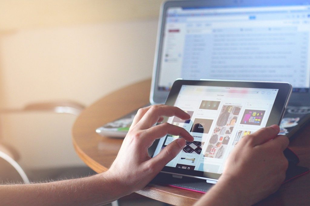 personne utilisant une tablette pour consulter un site de shopping en ligne avec un ordinateur en arrière-plan