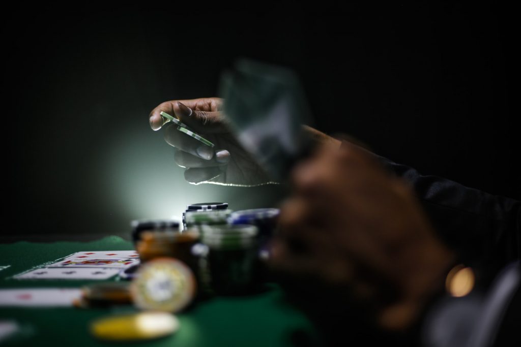 joueur tenant des jetons de poker autour d'une table de jeu avec cartes et argent
