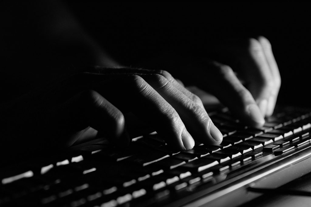 mains tapant sur un clavier d'ordinateur en noir et blanc