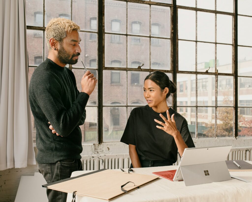deux professionnels discutent devant un ordinateur portable dans un bureau moderne