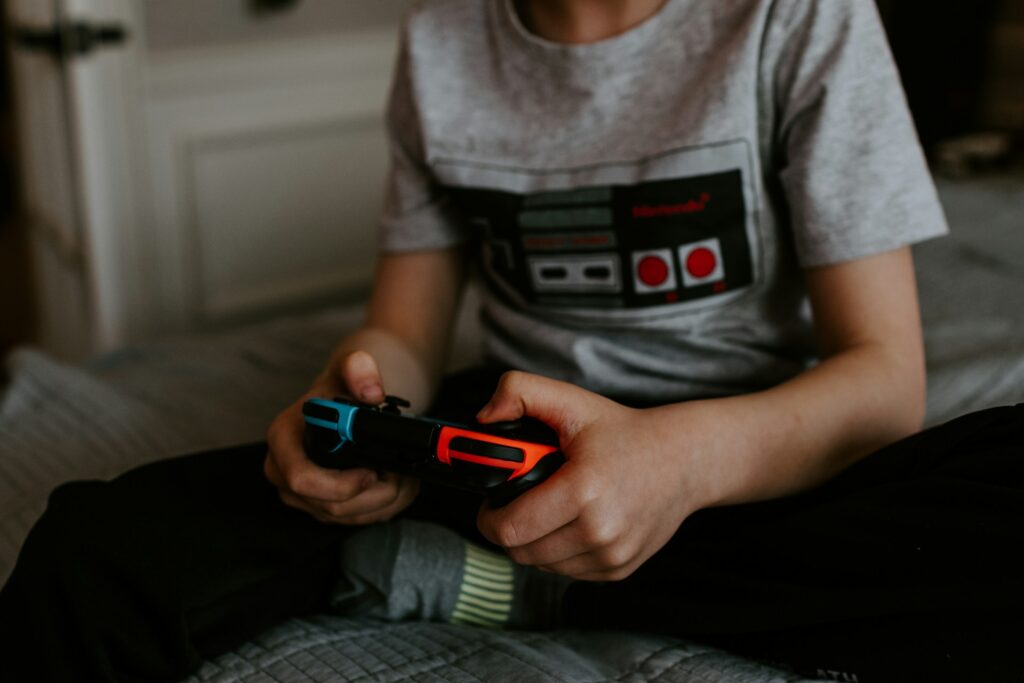 enfant tenant une manette de jeu rétro noire et rouge avec contrôleur bleu