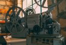 Close-up of a vintage film projector in a rustic, dimly lit room with stone walls.