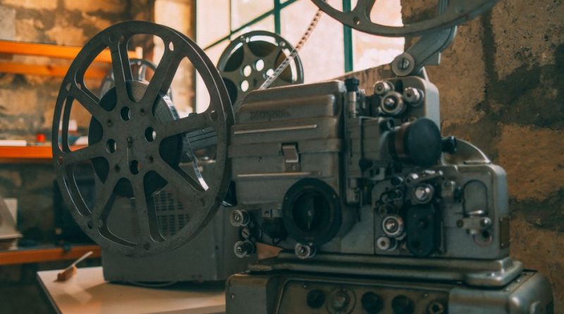 Close-up of a vintage film projector in a rustic, dimly lit room with stone walls.