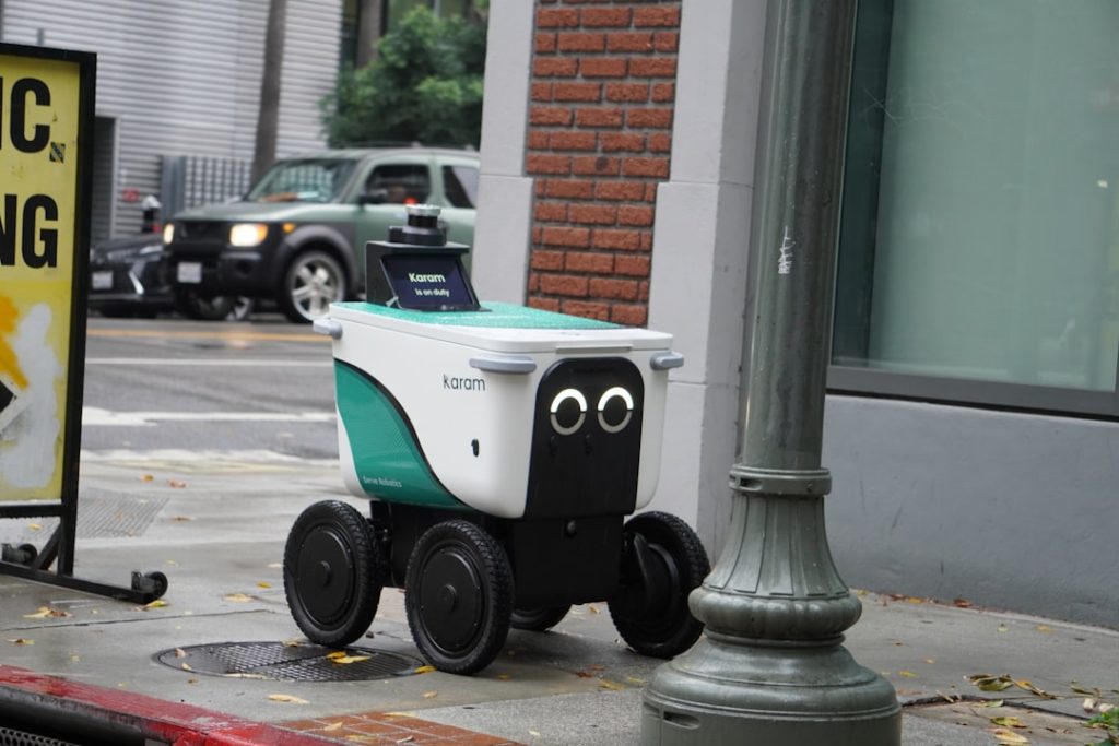A small delivery robot with googly eyes on a sidewalk