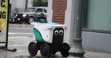 A small delivery robot with googly eyes on a sidewalk